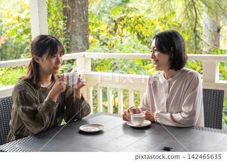 兩個女人在樹林中的咖啡館聊天。 兩個女人在樹林中的咖啡館聊天。 142465635