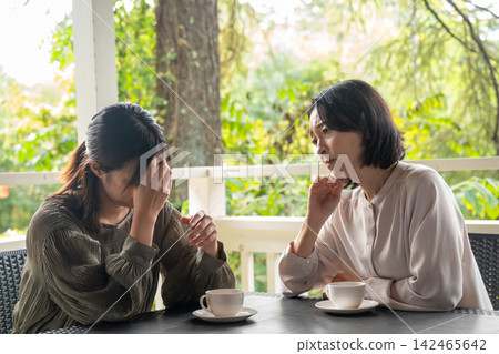 一位女士在別墅的露臺上傾聽朋友的煩惱。 一位女士在別墅的露臺上傾聽朋友的煩惱。 142465642
