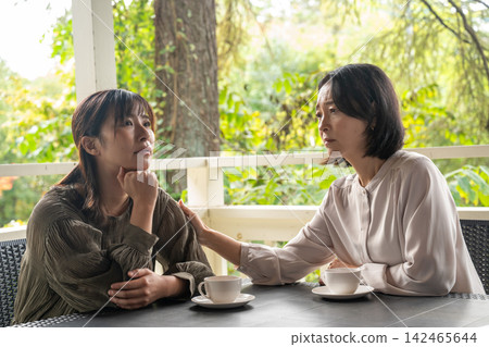A woman comforts her depressed friend at a cafe in the highlands. A woman comforts her depressed friend at a cafe in the highlands. 142465644