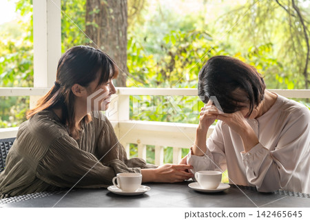 一位女士在露臺上安慰她情緒低落的朋友。 一位女士在露臺上安慰她情緒低落的朋友。 142465645