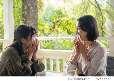 Female friends chatting with smiles on their faces on the terrace. Female friends chatting with smiles on their faces on the terrace. 142465652