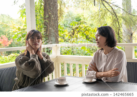 A woman gently comforts her friend on the terrace of a villa. A woman gently comforts her friend on the terrace of a villa. 142465665