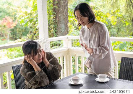 一位女士在露臺上認真地聽朋友說故事。 一位女士在露臺上認真地聽朋友說故事。 142465674