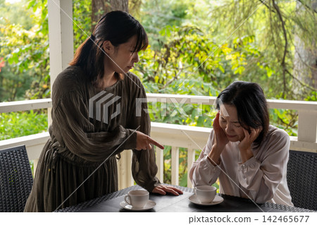 一位女士在別墅的露臺上認真地聽著朋友講述她的故事。 一位女士在別墅的露臺上認真地聽著朋友講述她的故事。 142465677