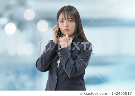 一位身穿西裝、表情嚴肅的女士正在打電話。 一位身穿西裝、表情嚴肅的女士正在打電話。 142465917