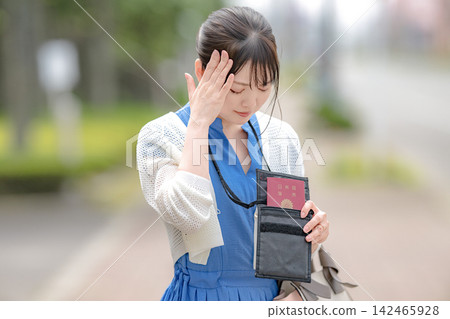 一位手拿護照、神情憂慮的女士。 一位手拿護照、神情憂慮的女士。 142465928