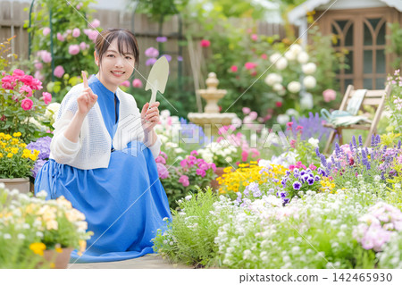 A woman holding a shovel and pointing in a flowerbed. A woman holding a shovel and pointing in a flowerbed. 142465930
