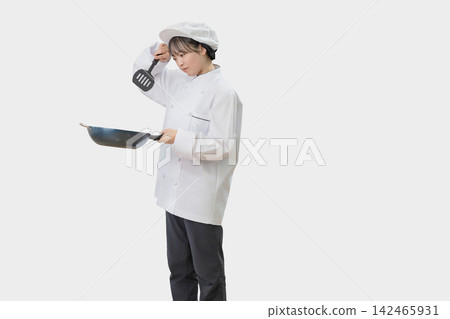 一位表情憂慮的女廚師,手裡拿著一口煎鍋。 一位表情憂慮的女廚師,手裡拿著一口煎鍋。 142465931