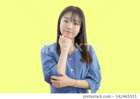 一位女子在黃色背景下擺出思考的姿勢 142465933