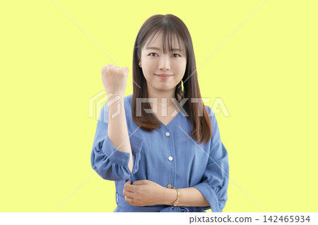 一名女子在黃色背景下擺出勝利姿勢。 一名女子在黃色背景下擺出勝利姿勢。 142465934