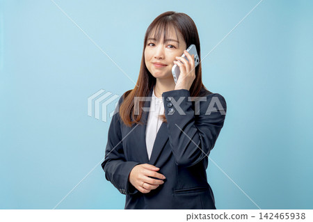 一位身穿西裝的女士正在用智慧型手機打電話。 142465938
