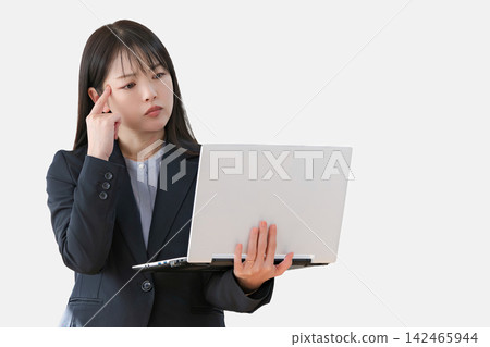 一位身穿西裝的女士看著筆記型電腦,陷入沉思。 一位身穿西裝的女士看著筆記型電腦,陷入沉思。 142465944