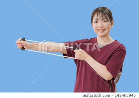 一位女性在藍色背景下使用健身器材。 142465946