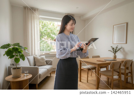 A woman in the living room operating a tablet A woman in the living room operating a tablet 142465951