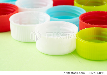 A light green background with bottle caps (lids) of various colors. A light green background with bottle caps (lids) of various colors. 142466098