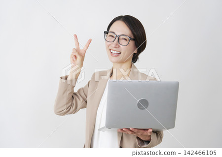 一位手持筆記型電腦的女商人，在白色背景前比出和平手勢。 142466105
