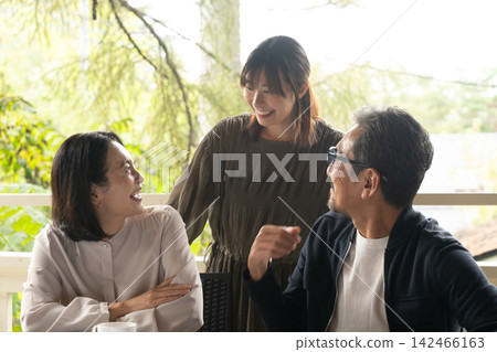 三個朋友在露台上放鬆微笑。 三個朋友在露台上放鬆微笑。 142466163