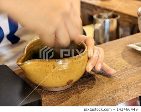 Barista whisking matcha in a ceramic bowl with motion blur action. Barista whisking matcha in a ceramic bowl with motion blur action. 142466449