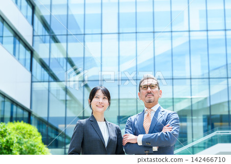 Business person standing in front of an office building Business person standing in front of an office building 142466710