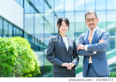Business person standing in front of an office building Business person standing in front of an office building 142466713