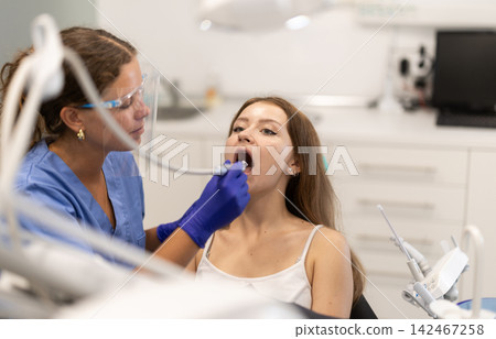 Woman dentist drilling and treating teeth of woman in clinic 142467258