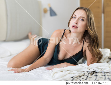 Adult woman posing on bed in bedroom Adult woman posing on bed in bedroom 142467352