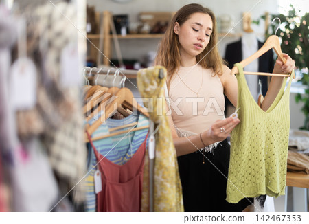 Selective young woman choosing something for summer in clothing store Selective young woman choosing something for summer in clothing store 142467353