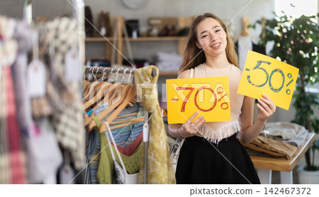 Portrait of woman holding sign saying 70 percent discount in clothing store 142467372