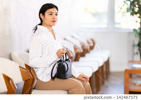 Woman sits in waiting room, queue awaiting Woman sits in waiting room, queue awaiting 142467375