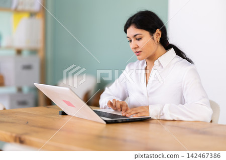 Female works on laptop in room Female works on laptop in room 142467386