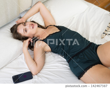 Contented woman in nightgown wakes up after good sleep in bed Contented woman in nightgown wakes up after good sleep in bed 142467387
