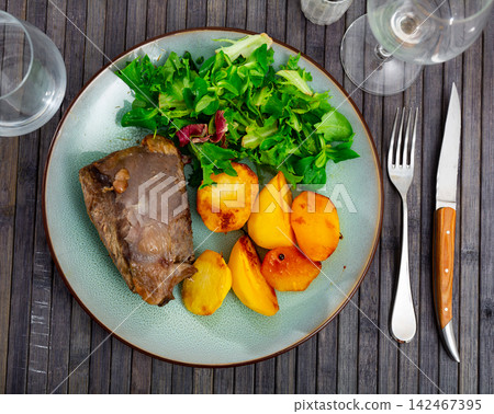 Baked beef with vegetable garnish of potato slices and greens Baked beef with vegetable garnish of potato slices and greens 142467395