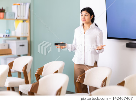 Woman with remote control in lecture hall 142467407