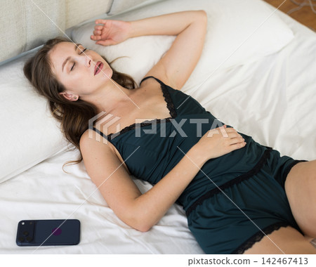 Beautiful woman in nightgown sleeping on the bed in bedroom at home Beautiful woman in nightgown sleeping on the bed in bedroom at home 142467413