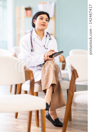 Female doctor at meeting listens to teacher and and using tablet to write down notes Female doctor at meeting listens to teacher and and using tablet to write down notes 142467417