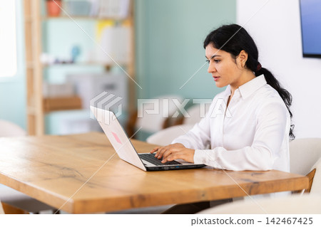 Female works on laptop in room Female works on laptop in room 142467425