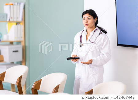 Woman doctor with remote control in lecture hall 142467442