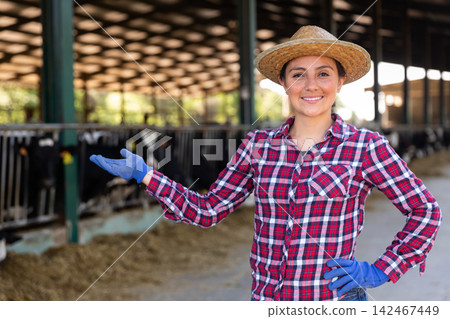 Female farmer engaged in breeding of cows posing in cowshed Female farmer engaged in breeding of cows posing in cowshed 142467449