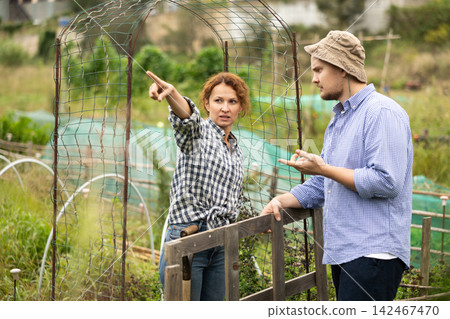 Woman quarreling with male neighbor, talking through fence Woman quarreling with male neighbor, talking through fence 142467470