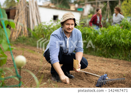 Guy is planting seeds in open ground 142467471