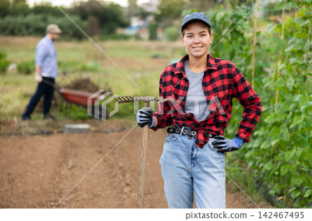 Portrait of girl holding a rake in farmer field 142467495