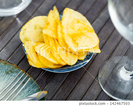 Crispy potato chips in cup on table 142467503