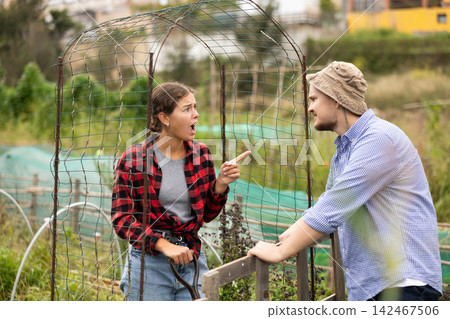 Angry girl quarreling with male neighbor, talking through fence Angry girl quarreling with male neighbor, talking through fence 142467506