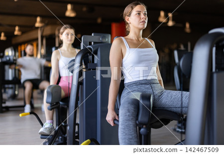 Young woman training her leg muscles on machine Young woman training her leg muscles on machine 142467509