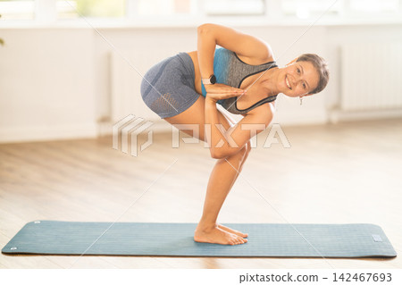 Sportive girl practicing chair pose of yoga in light room 142467693