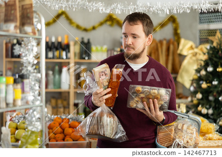 Man chooses turron, panellets and panettone Man chooses turron, panellets and panettone 142467713