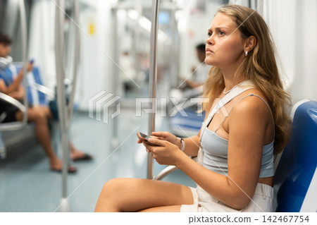 Young girl sitting in wagon holding mobile phone in hand 142467754