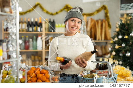 Female shopper chooses between wine and champagne while shopping at supermarket Female shopper chooses between wine and champagne while shopping at supermarket 142467757
