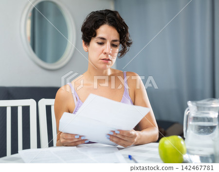Girl with papers at table working with documents Girl with papers at table working with documents 142467781