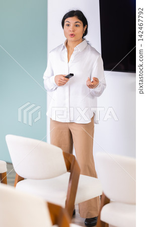Woman with remote control in lecture hall Woman with remote control in lecture hall 142467792